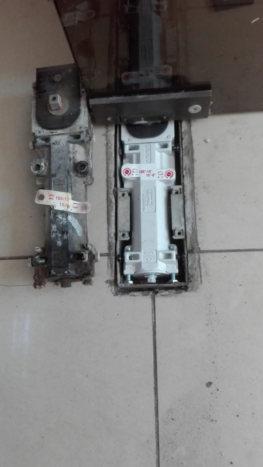 Quicio hidráulico deteriorado y mecanismo de reemplazo observados en un acceso de puerta de vidrio